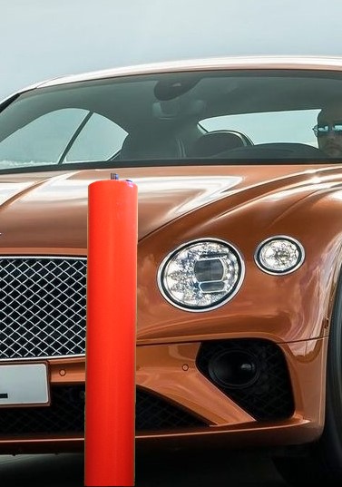 Oranje Bentley voor een rode verzinkbare beveiligingspaal van RhinoSystems